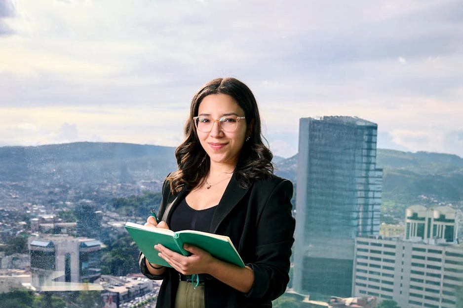 Una persona sorridente che scrive su un taccuino in un ufficio creativo